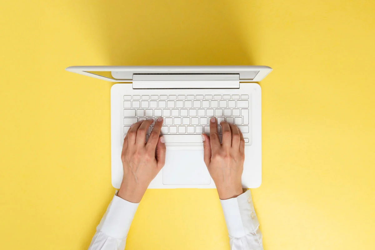 decorative image hands on white laptop with yellow background