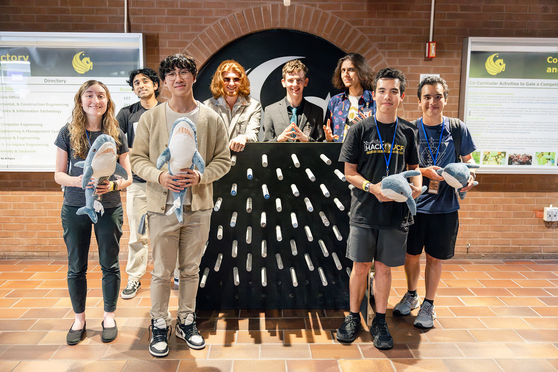 group of stduents standing in front of and behind a plinko board